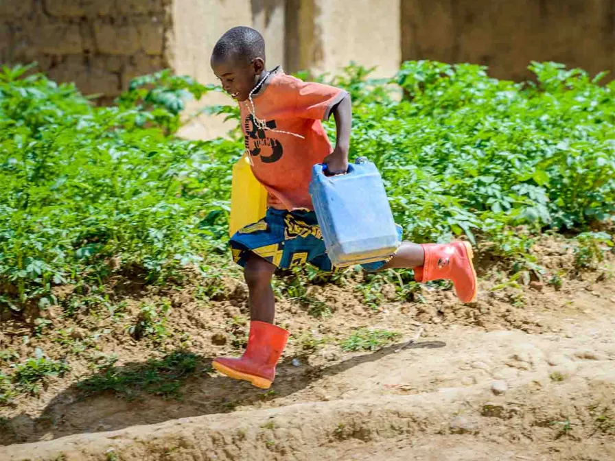 Kind rennt mit zwei Wasserkanistern