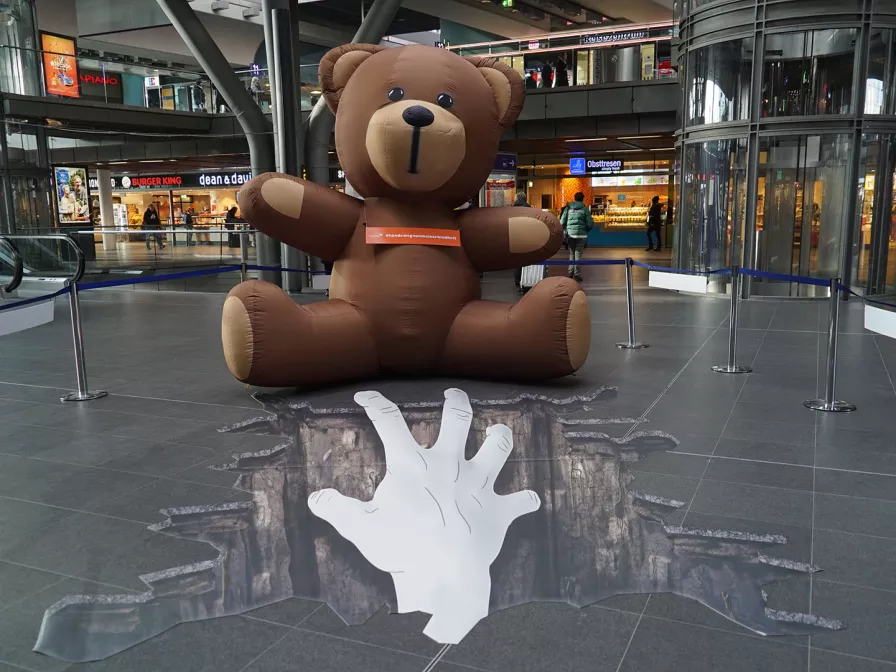 Ein riesiger Teddy steht symbolisch für bedrohte Kindheit