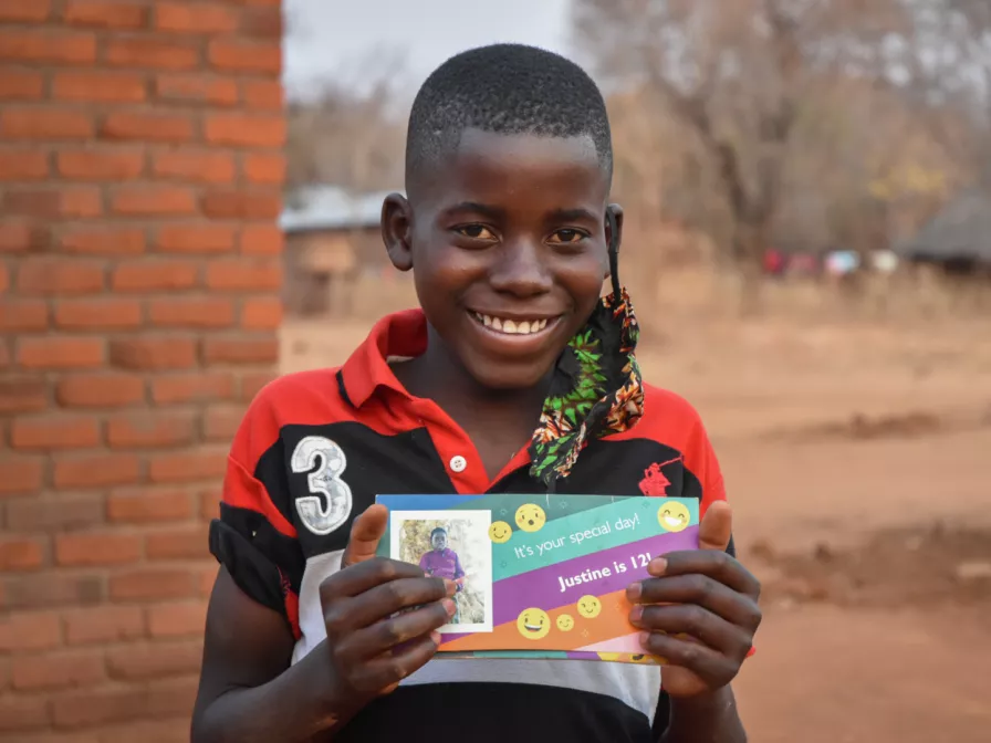 Justine aus Sambia hält den Geburtstagsbrief seines Paten in der Hand