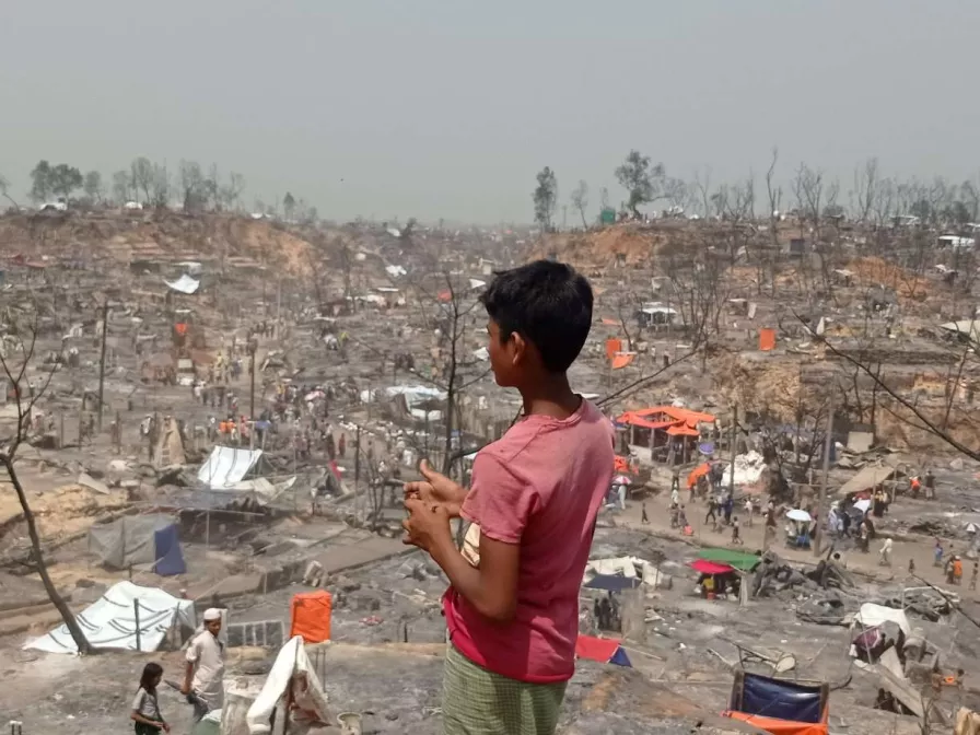 Ein Junge schaut auf das abgebrannte Flüchtlingslager der Rohungya