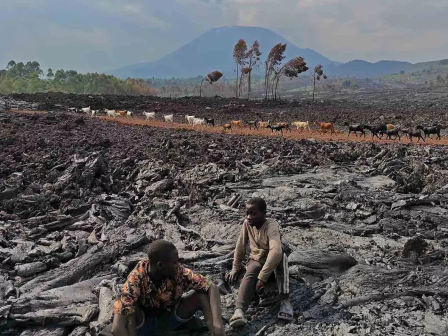 Kinder sitzen auf dem durch den Vulkanausbruch entstandenen Lavafeld