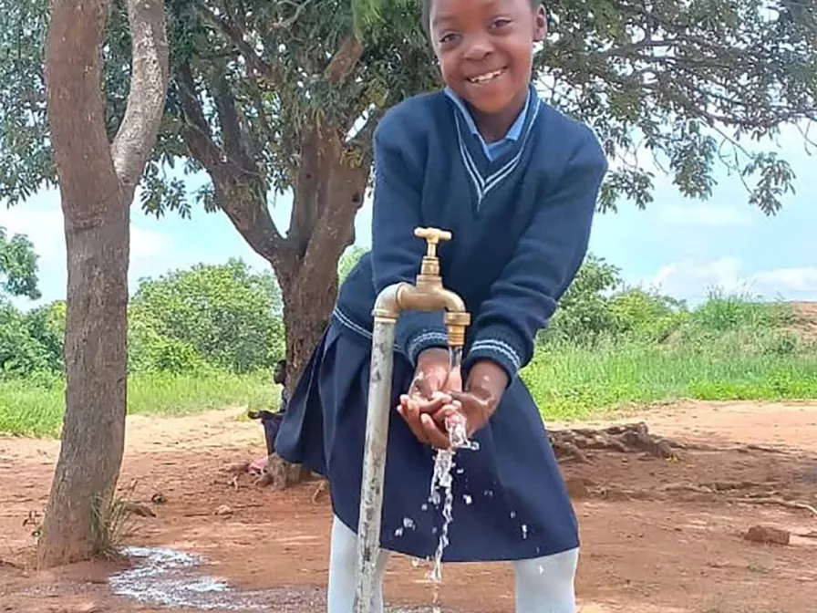 Mädchen in Sambia vor einem Wasserhahn