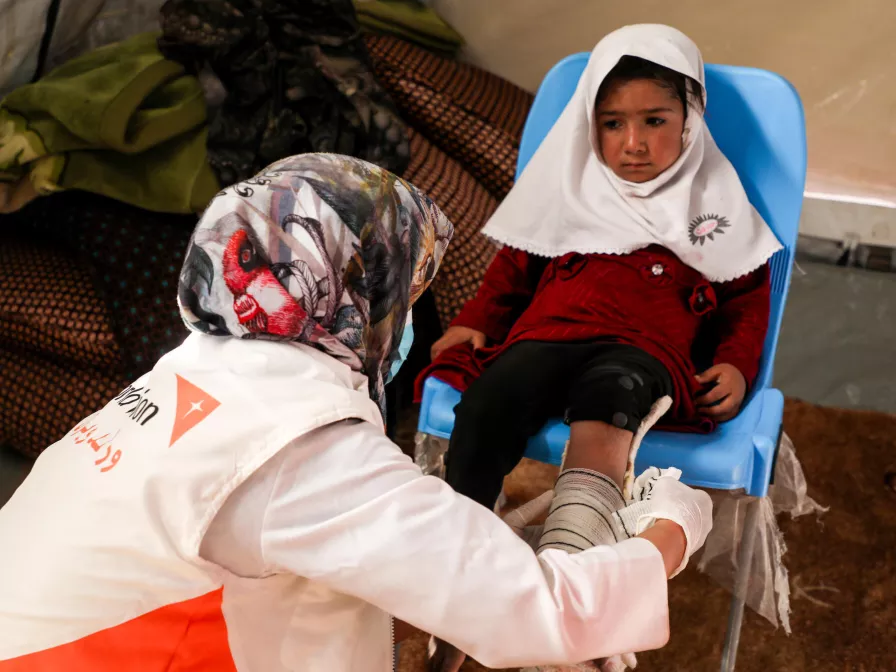 Erdbeben in Afghanistan: Ein World Vision-Mitarbeiterin versorgt ein verletztes Mädchen.
