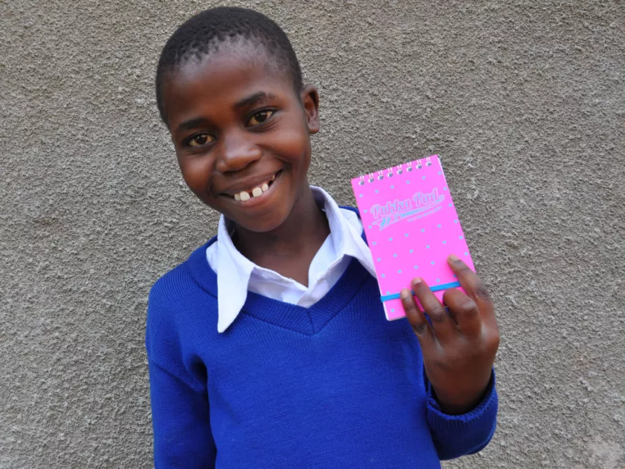Florence aus Tansania mit einem Notizbuch von ihrem Paten.