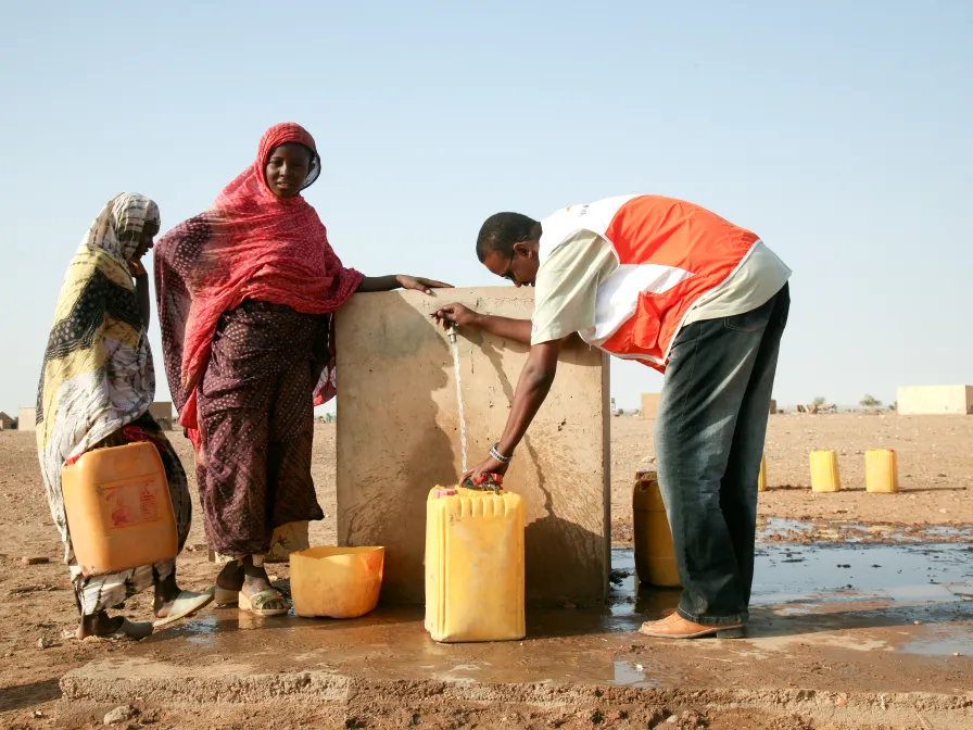 World Vision Mitarbeiter hilft am Brunnen