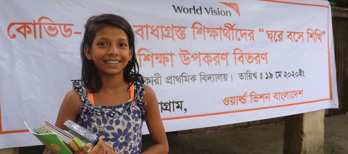 Ein Mädchen nimmt Lernmaterial von World Vision entgegen.