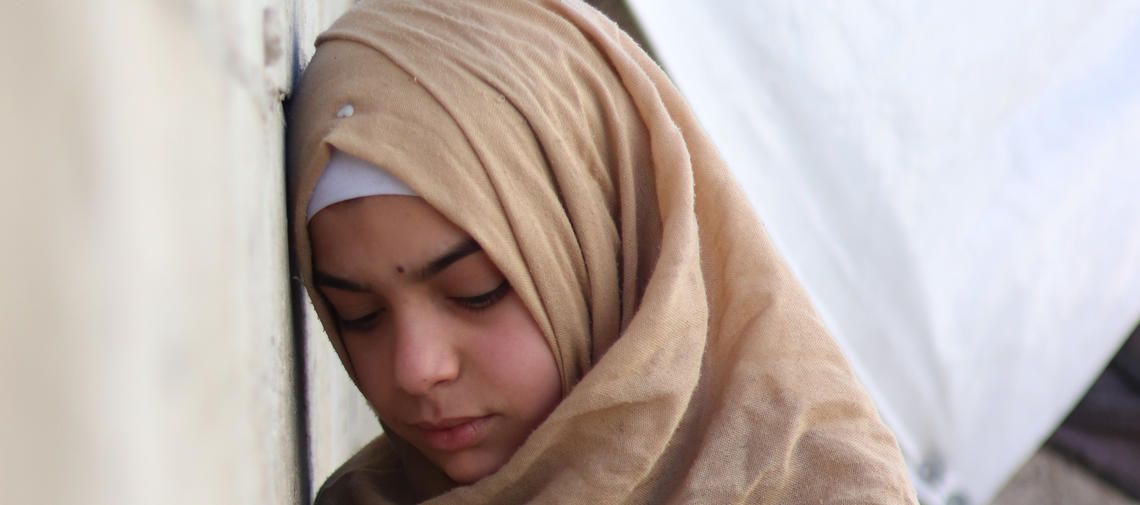 Syrisches Mädchen lehnt seinen Kopf an eine Wand