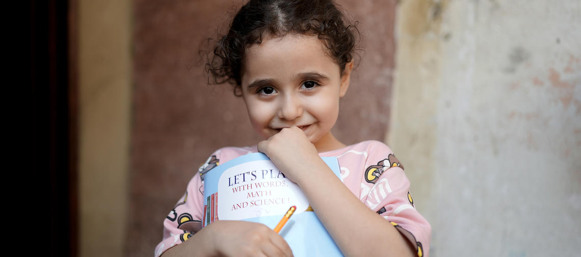 Ein von World Vision unterstütztes Mädchen im Libanon hält ein Mathebuch in den Händen.