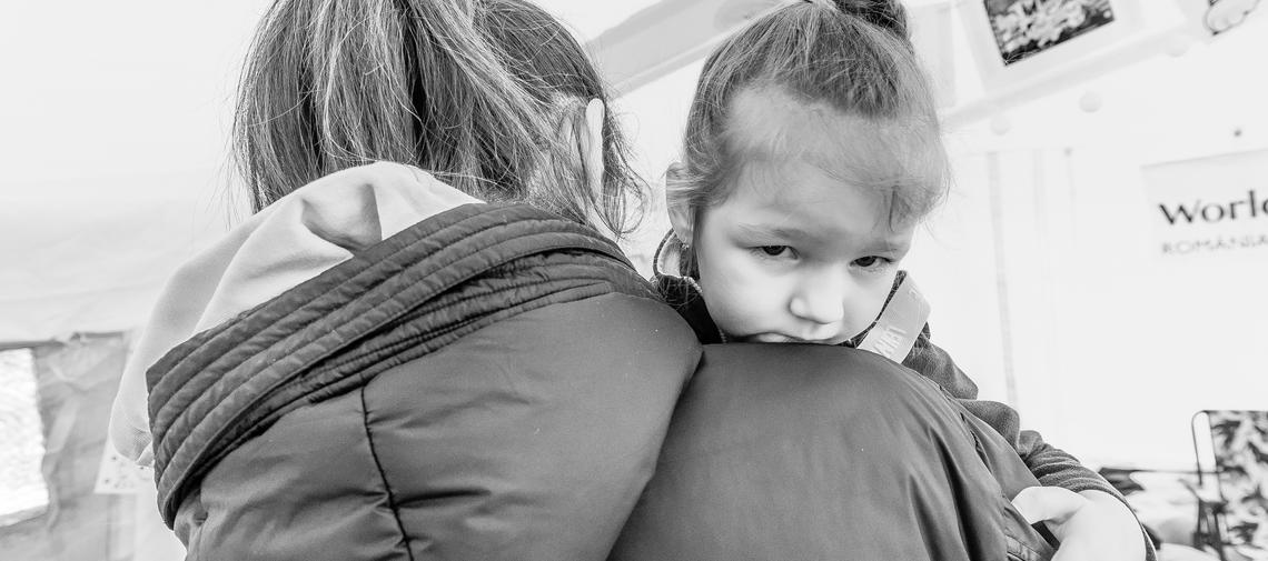 Ukrainische Mutter von hinten mit kleinem Mädchen auf dem Arm