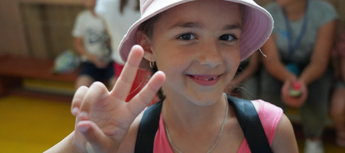 Mädchen aus der Ukraine macht Victory-Zeichen in einem Ferien-Camp.