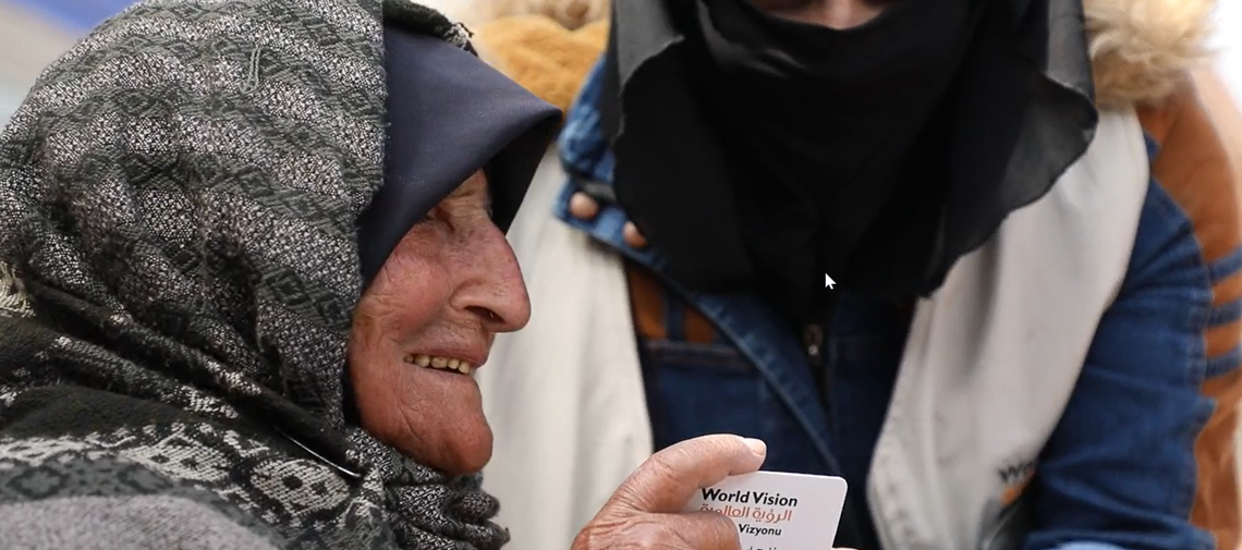 Eine ältere Syrerin erhält nach dem Erdbeben eine Karte für den BEzug vpn Bargeld.