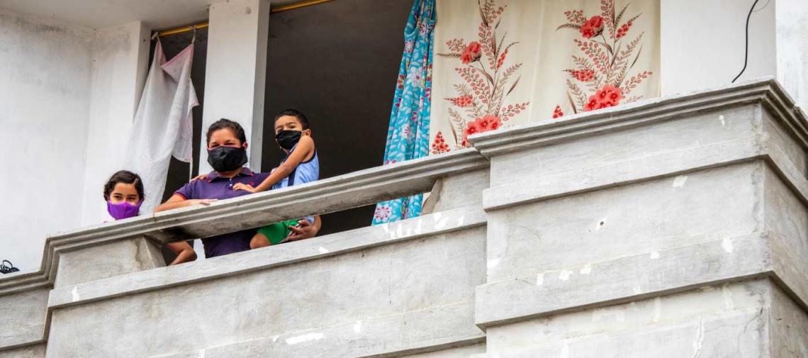 Migranten-Familie aus Venezuela mit Mundschutz auf einem Balkon