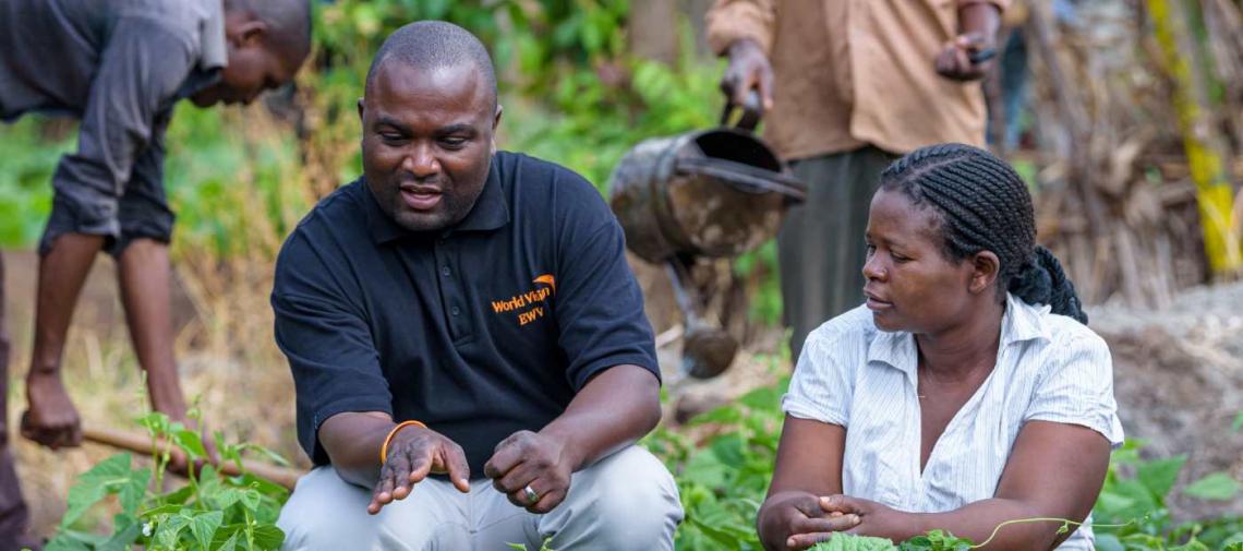 Landwirtin aus Malawi diskutiert mit einem World Vision-Mitarbeiter über Anbaumethoden.
