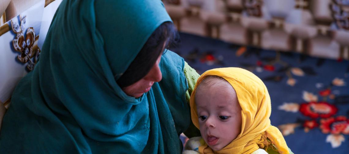 Afghanische Frau mit unterernährtem Kleinkind auf dem Arm