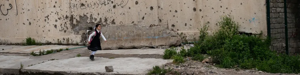 Ein Schulkind läuft an zerschossenen Häusern in Mossul vorbei. Foto: World Vision / Brett Tarver
