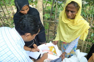 Ein World Vision-Mitarbeiter prüft den Inhalt eines Nahrungsmittel-Pakets für eine Flüchtlingsfamilie in Bangladesch
