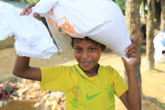 World Vision-Nothilfe in Bangladesch: Ein aus Myanmar geflüchteter Junger trägt einen Sack Reis nach Hause.