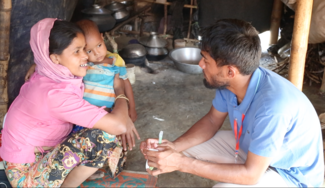 Ein Mitarbeiter von World Vision berät eine Mutter mit Kleinkind im Flüchtlingslager in Bangladesch