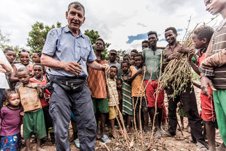 Agrarökonom Tony Rinaudo demonstriert afrikanischen Landwirten und ihren Familien wie sie aus Baumstümpfen neue Bäume heranziehen können.