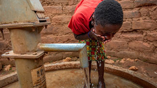 Brendah probiert saubers Wasser aus dem Brunnen