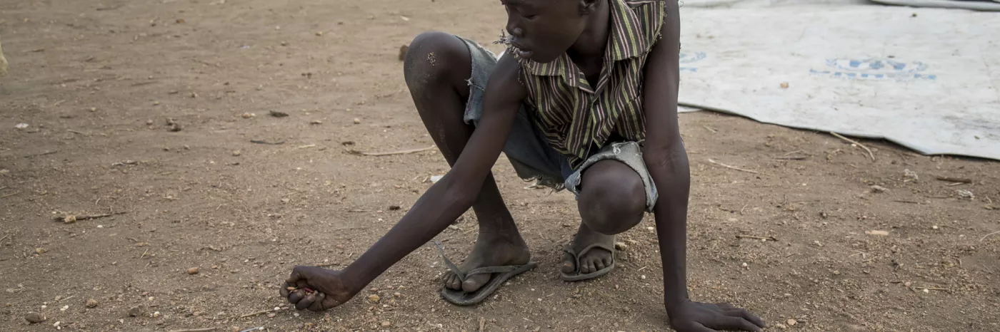 Hungriger Flüchtling aus Südsudan sammelt Essen auf