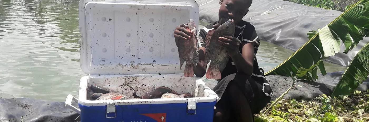 Mädchen zeigt Tilapia aus Fischzucht in Kenia - gefördert von World Vision