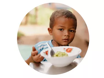 World Vision Patenschaft ermöglicht Bildung: Junge isst aus einer Schüssel