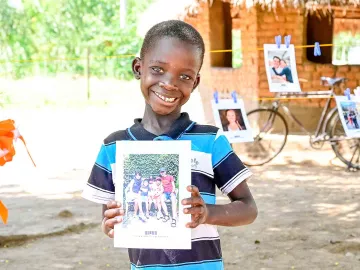 World Vision Wunschpatenschaft: Ein kleiner Junge hält das Bild seines Paten in die Kamera