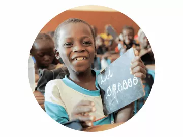 World Vision Patenschaft ermöglicht Bildung: Junge hält lächelnd einen Brief hoch