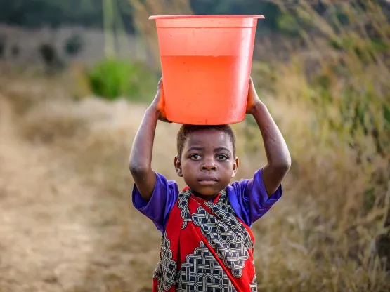 Kinder mit Wasserkübel auf dem Kopf