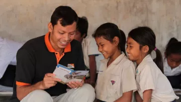 World Vision Mitarbeiter liest zwei Patenkindern in Kambodscha die Post ihrer Paten.