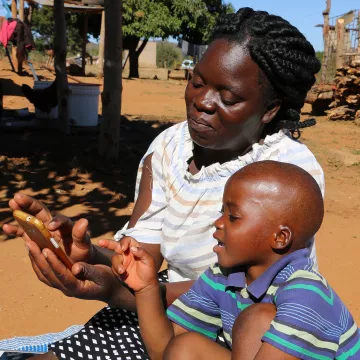 Betty Mhlanga testet mit ihrem Sohn Tamuka in Simbabwe den Audio-Schulunterricht auf dem System VIAMO, unterstützt von World Vision