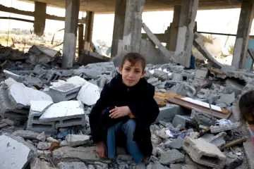 Junges palästinensisches Mädchen sitzt in den Trümmern eines Hauses.