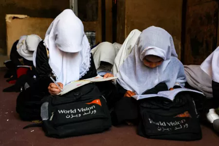 Zwei afghanische Mädchen schreiben in ein Schulbuch