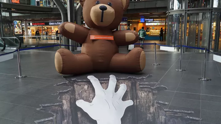 Ein riesiger Teddy steht symbolisch für die bedrohte Kindheit dieser Kinder.