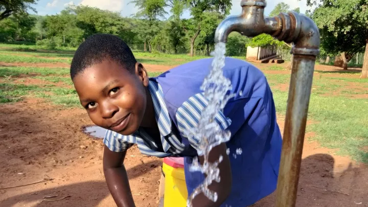 Ein Mädchen holt sauberes Wasser am Brunnen