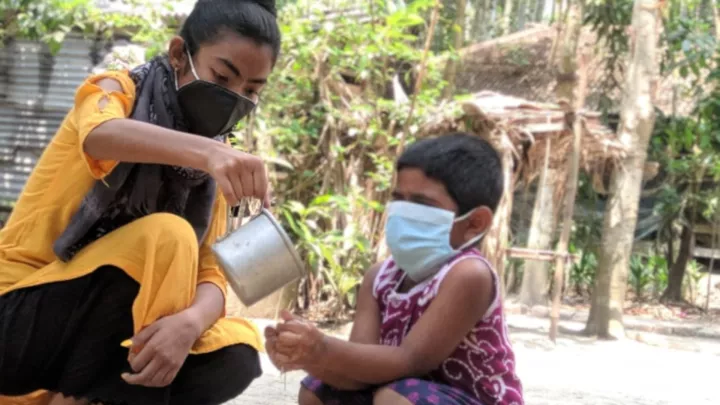 Farzana aus Bangladesch zeigt einem kleineren Kind richtiges Händewaschen.