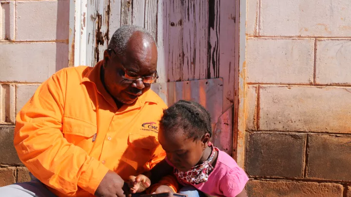 Vater und Tochter testen den Audio-Schulunterricht mit VIAMO in Simbabwe