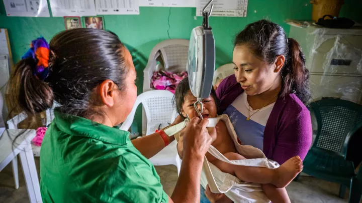 Gesundheitshelferin Carmen aus Honduras wiegt ein kleines Mädchen.