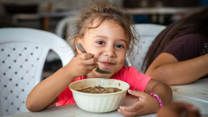 Ein Mädchen aus Venezuela freut sich über eine warme Mahlzeit