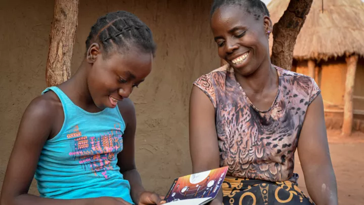 Patenkind Precious liest mit ihrer Mutter ihre Glückwunschkarte.