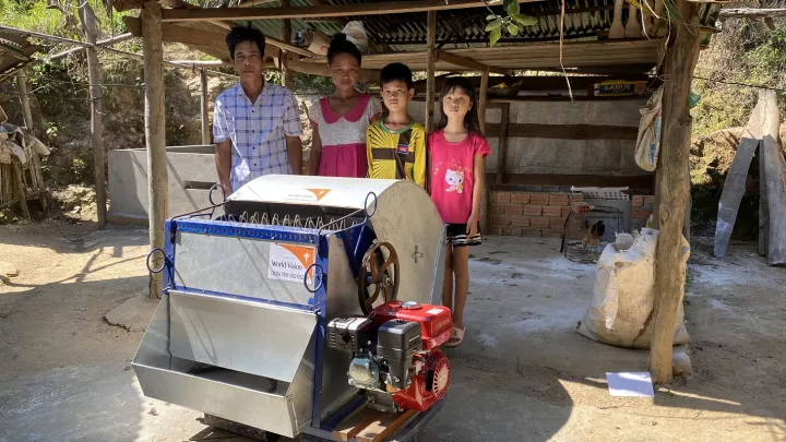 Eine Familie steht stolz hinter der Reisdreschmaschine