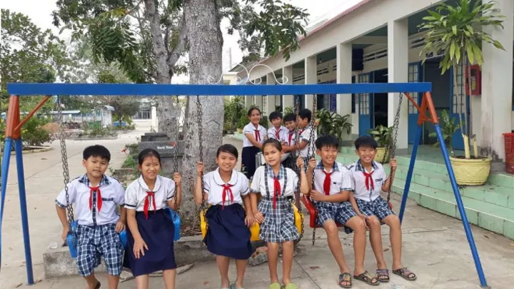 Gruppenbild von Kindern auf einer Schaukel vor ihrer Schule