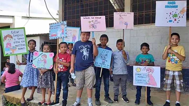 Kinder aus Guatemala mit Plakaten mit Infos über das richtige Händewaschen.