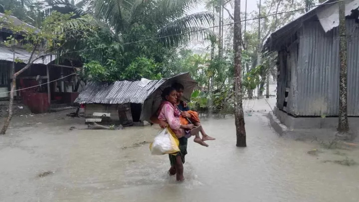 Alte Frau wird von Mann aus den Fluten getragen