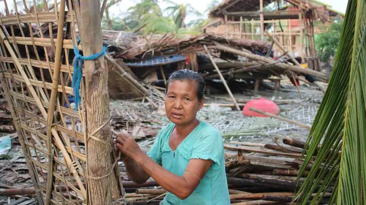 Frau vor ihrem durch einen Wirbelsturm zerstörten Haus in Myanmar