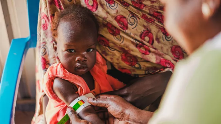 Hebamme Paula Atimango untersucht den Ernährungszustand eines Babies in einer von World Vision betriebenen Nothilfe-Klinik an der Grenze zu Sudan.