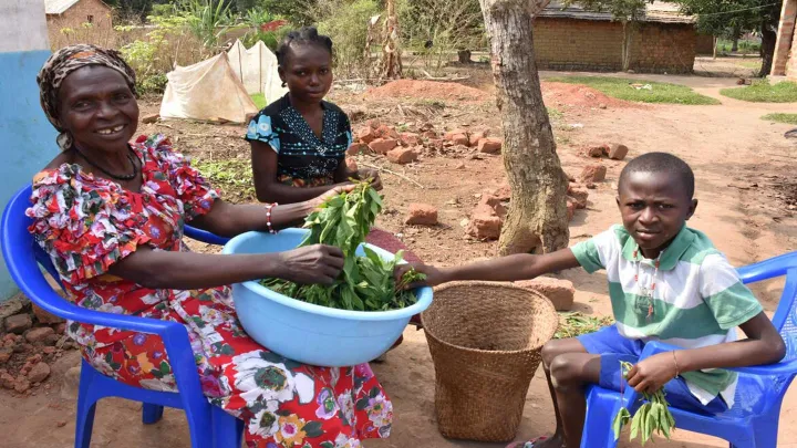 Familie beim Schälen von Maniokblättern