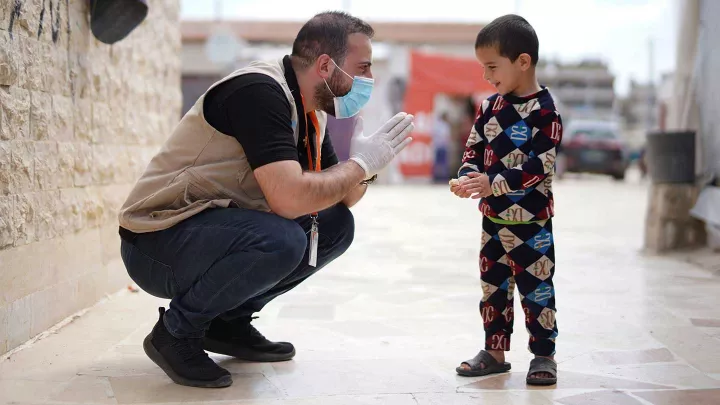 WV Mitarbeiter spricht mit einem Flüchtlingskind