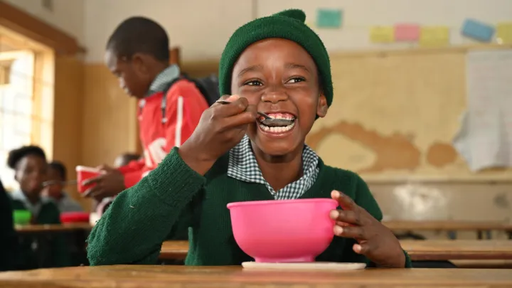 Ein Grundschüler aus dem südlichen Afrika freut sich über seinen Porridge in der Schule.